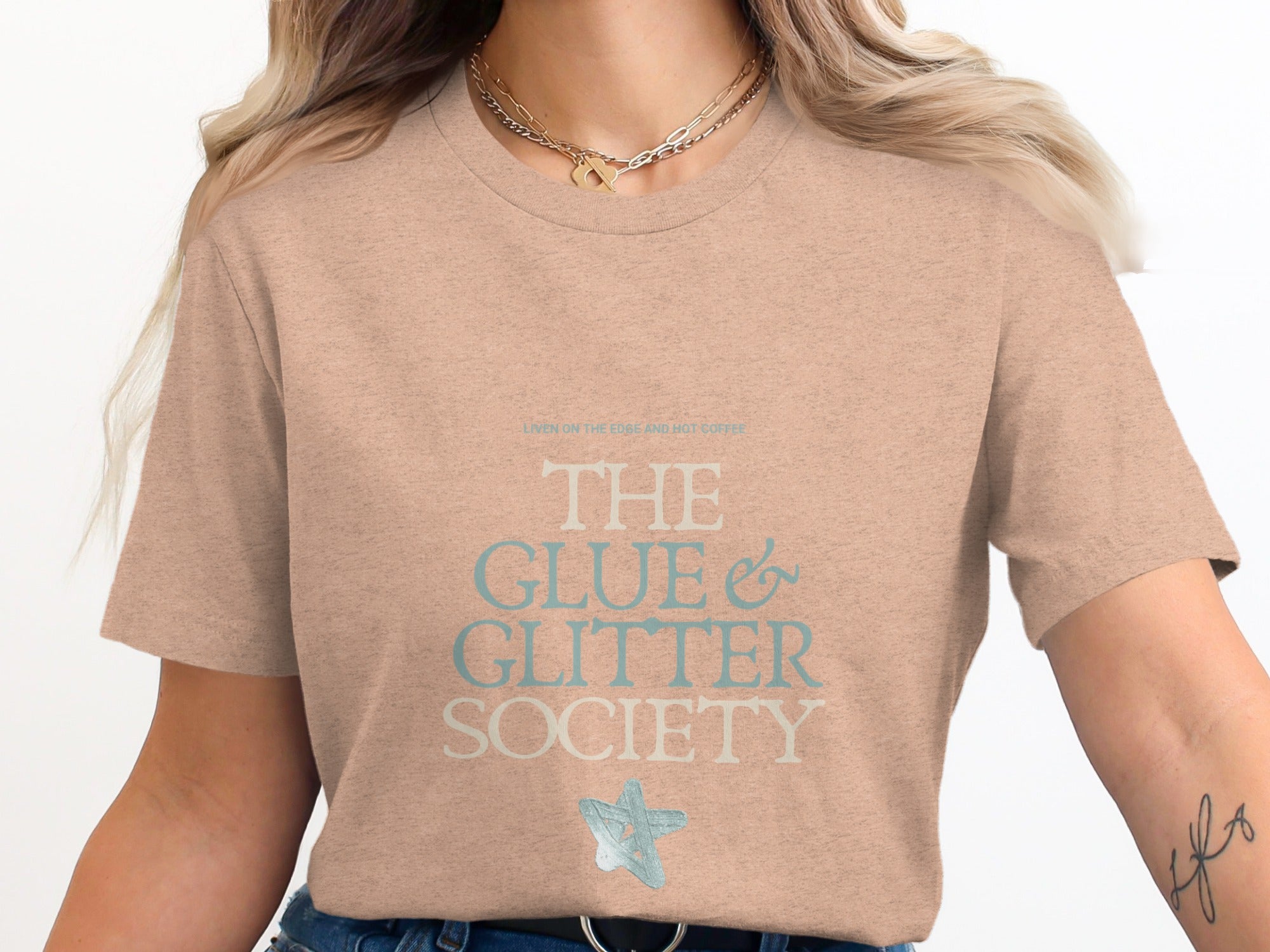 Light tan t-shirt with "THE GLUE & GLITTER SOCIETY" in blue text.